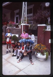 Photograph of Residents relax on the steps of a rowhouse, Baltimore MD, September 1985. Photo ID: na059. North Avenue Collection (R0090-NA), University of Baltimore Special Collections &amp; Archives.