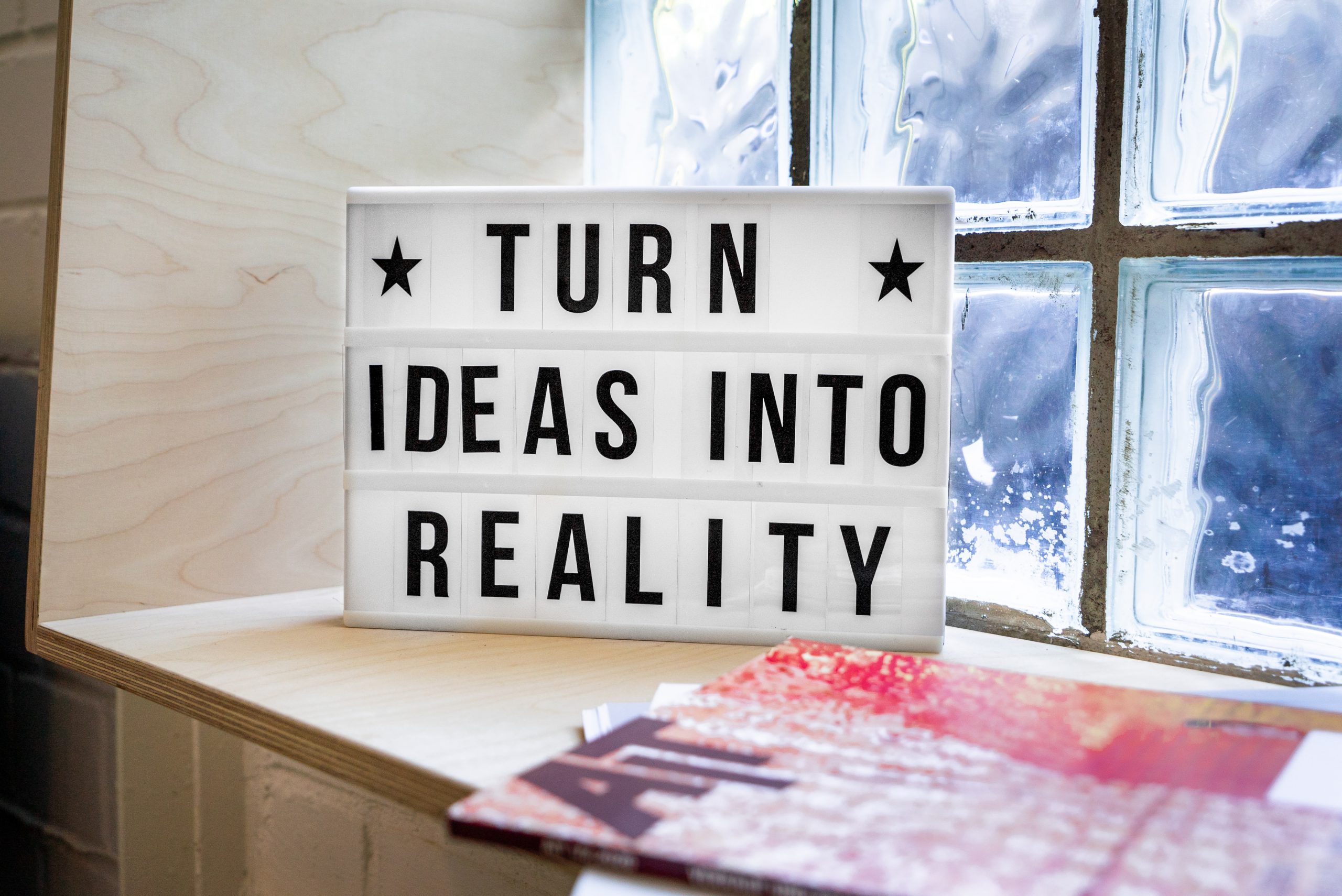 white and black wooden quote board with inspirational quote "turn ideas into reality"
