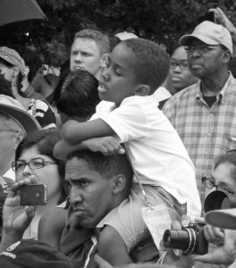 Young boy sitting on man's shoulders.