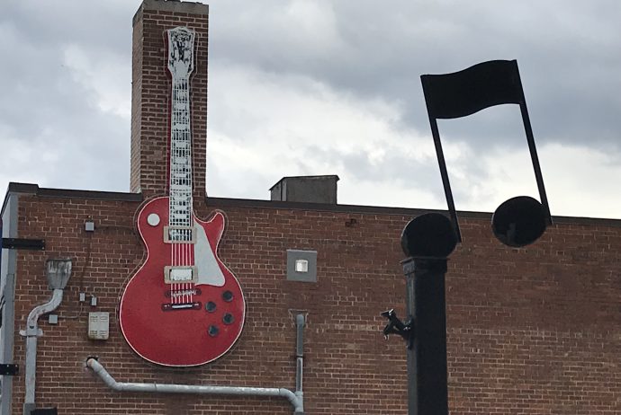 large guitar and music note decal on the side of a brick building